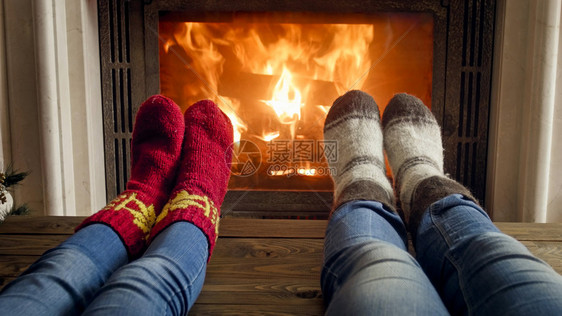 在壁炉旁躺着的一对穿牛仔裤和编织羊毛袜的夫妇近视图像中一对穿着牛仔裤和编织羊毛袜的夫妇在壁炉旁躺着的近相照片图片