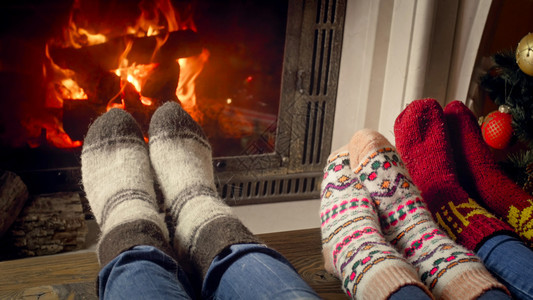 穿着毛绒袜子的家庭与儿童一起坐在居室与燃烧的壁炉一起躺在居室里图片