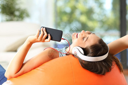 在家客厅用耳机和智能电话听音乐时图片