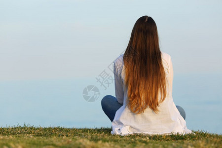 独自看着天空坐在草地上的女人背面肖像图片素材