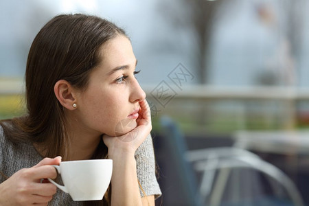 在一个雨天餐厅露台看望着拿咖啡杯的阴道女人图片