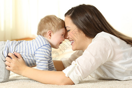 一个亲的母侧面肖像和在家地毯上躺着的婴儿开玩笑图片