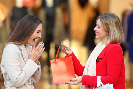 一个快乐的沙巴侧面给一个朋友送礼物在冬天的街上商业中心的一个朋友图片