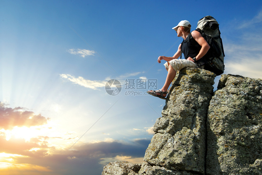观光客坐在岩石上寻找边缘悬崖上的太阳图片
