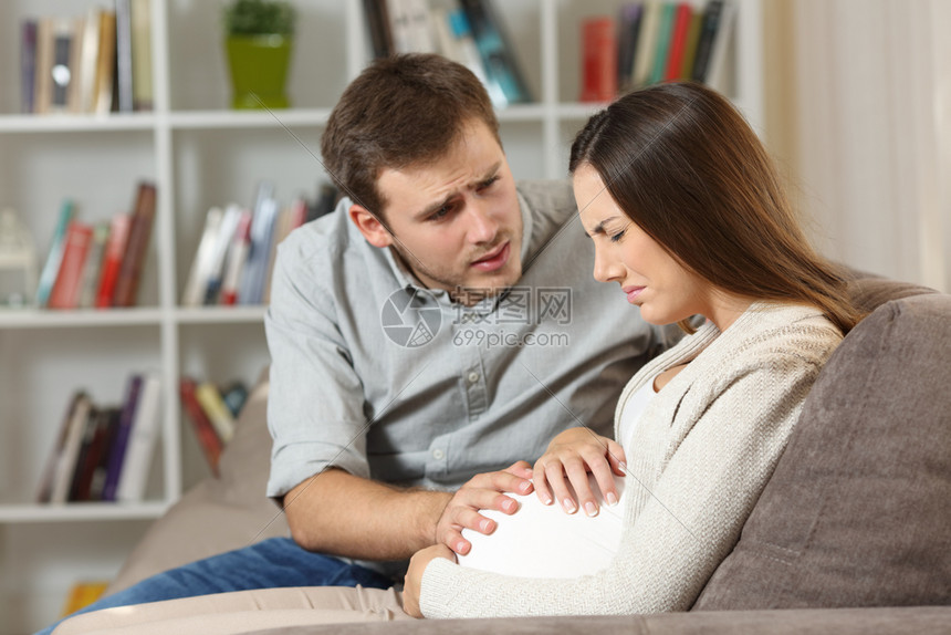 孕妇肚子痛丈夫安慰她坐在家中沙发上