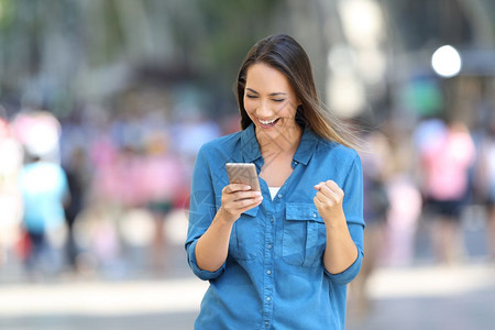 一位在街上用智能电话阅读好消息的兴奋女性正面观感图片