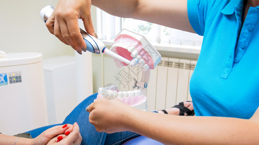 牙科医生用电刷对病人进行洗牙教育的近视图像牙科医生用电刷对病人进行洗牙教育的近视照片图片