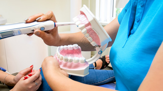 显示如何用电牙刷来照顾齿的科医生近照显示如何用电牙刷来照顾齿的科医生近照图片