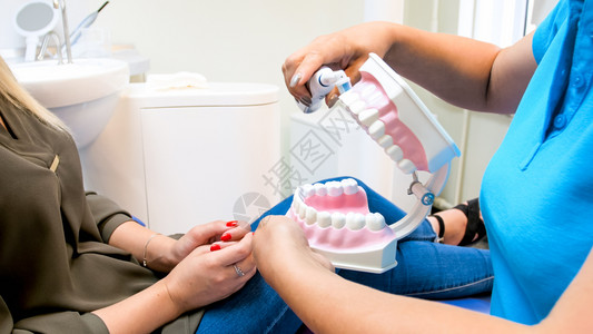 牙科医生的近视图像显示她的病人如何用电牙刷适当清洗齿科医生的近视照片显示她的病人如何用电牙刷适当清洗齿图片