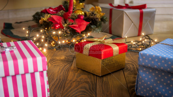 圣诞树下木地板上带丝的彩色礼品盒近照图片