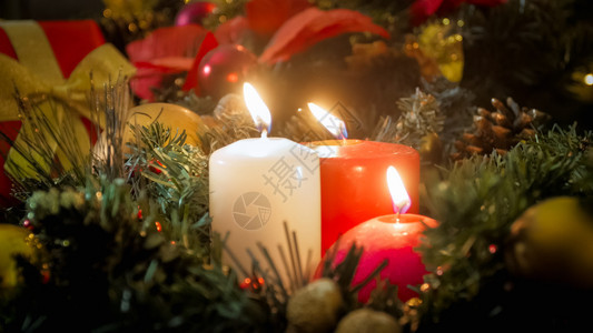 三个蜡烛和美丽的圣诞花圈紧贴照片图片