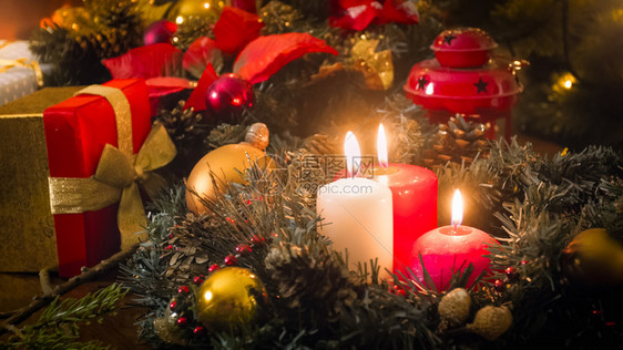 圣诞节前夕三支燃烧的蜡烛礼品和花圈的照片图片