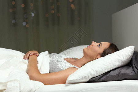 一个失眠女孩无法睡在床上的侧视图肖像图片