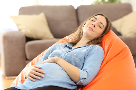 气血不足 疲劳  乏力在家客厅睡pouf的疲倦孕妇肖像背景
