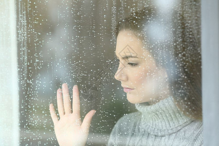在家下雨的一天个悲伤的女孩透过窗户看望着一个女孩的肖像图片