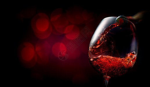 酒倒在深红背景的葡萄酒杯中图片