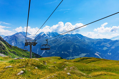 瑞士阿尔卑斯山高地的绿色青草山高地夏季景色有雪峰和电缆的汽车梯支持图片