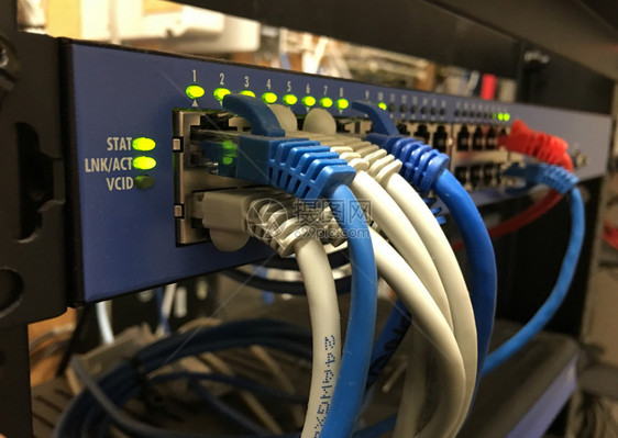 蓝色白橙网络电缆挂在酒店通讯服务器架前图片
