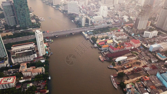 泰国曼谷市日落时区下城金融和摩天大楼内ChaoPhraya河和Taksin桥的曲线空中观察图片