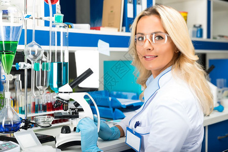 在科学化实验室从事防护眼镜和手套研究的有吸引力年轻女科学家图片