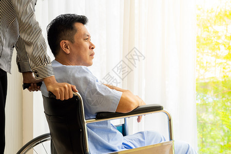 老人病和他坐轮椅的亲属正在透过窗户看望着图片