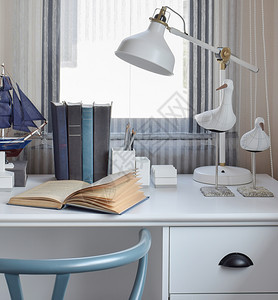 家里现代工作区的白色桌子配有木制椅书和灯具图片