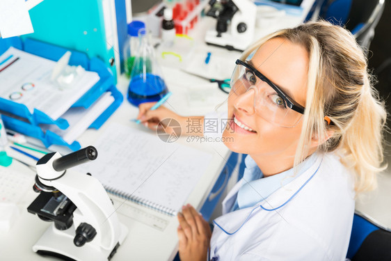 在科学化实验室编写保护眼镜研究报告的年轻有吸引力女科学家图片