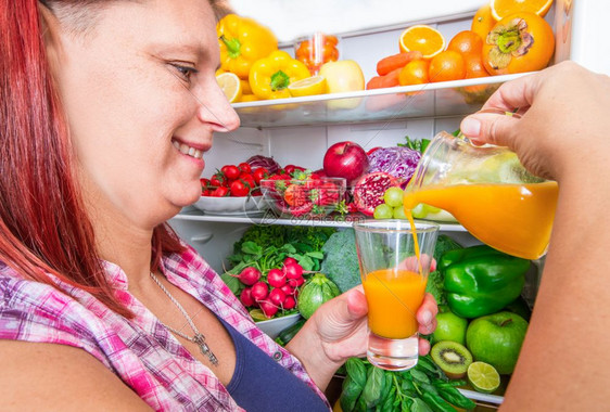 女人从冰箱里倒水果汁图片