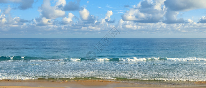 海边晴朗的阳光明媚一天黄沙和蓝海在天空背景之下图片