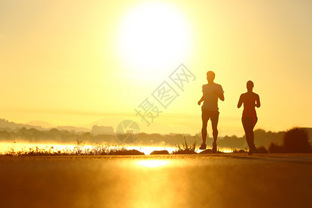 男人和女在日出时沿海公路上奔跑图片