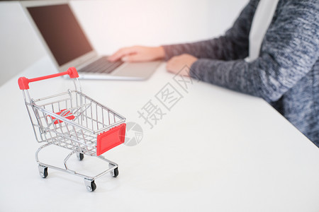 带有膝上型计算机的小妇女购物车用于互联网在线购物概念图片