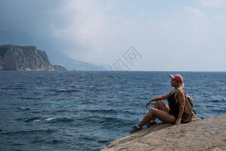 一个金发女孩坐在山顶看着海滩放松自然旅行图片