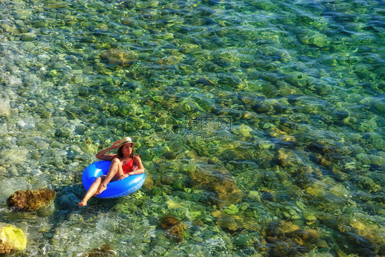 美丽的年轻女士带充气环放松在海上图片