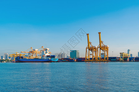 进出口企业的集装箱货船和城市的物流国际货中午和蓝天用起重机将货物运往港口背景图片