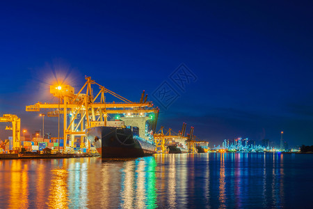 进出口企业的集装箱货船和城市的物流国际货日落时用起重机将货物运往港口图片