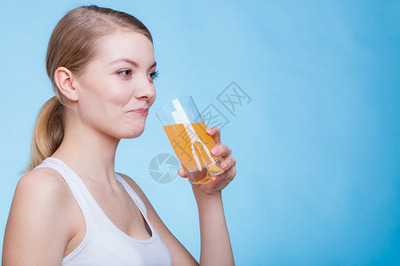 以蓝背景拍摄的演播室喝橙色饮料或果汁的妇女喝橙色饮料或果汁的妇女图片