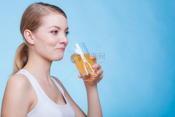以蓝背景拍摄的演播室喝橙色饮料或果汁的妇女喝橙色饮料或果汁的妇女图片