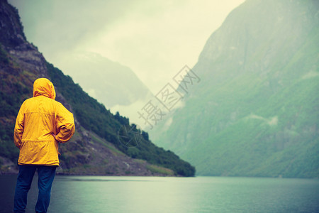 旅游假期和行在挪威斯堪的纳维亚男观光客在看山和fjordSognefjord挪威斯堪的纳维亚州Misty雾天雨季旅游者在看山和f图片