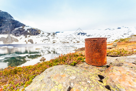 古老的生锈可以丢弃在湖岸美丽的山地背景球生态旧的锈可以丢弃湖岸图片