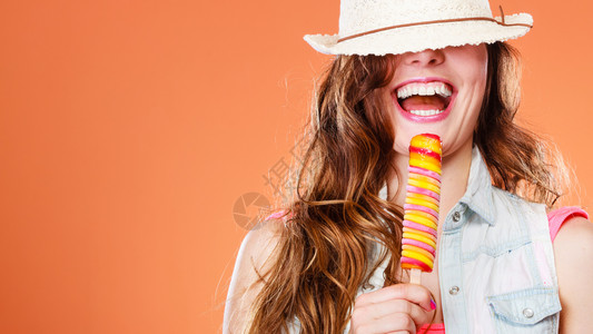 暑假快乐概念有趣的快乐女人蒙着眼睛戴草帽吃了冰淇淋橙色背景的冰淇淋图片