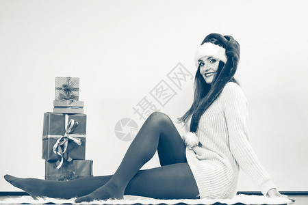 戴圣诞冬季幸福概念戴圣诞帮手帽子带许多礼物盒黑白相片的女子做圣诞礼物的快乐女人图片