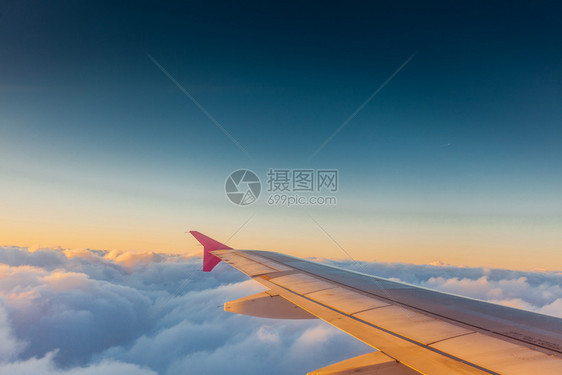 旅客在飞机窗玻璃前拍摄日落图片