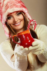 穿着毛帽的笑脸女人拿着红杯喝饮料甜的甘蔗带着杯子和甘蔗的圣诞女孩图片