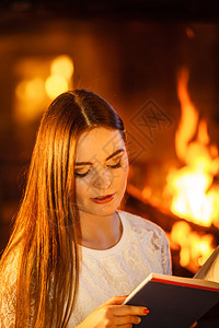 女孩在壁炉上读书年轻女孩暖和放松冬天在家女人壁炉上读书冬天在家放松图片