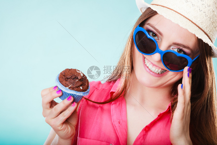 欢乐的夏天时装女人穿着草帽心戴墨镜的手持蓝底蛋糕图片