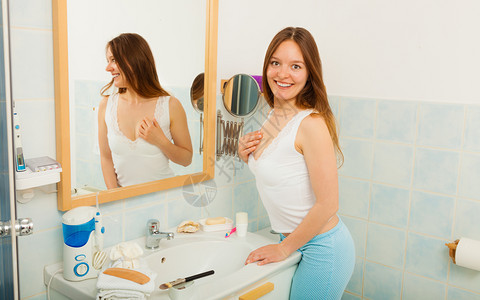 在浴室里没有化妆品的快乐少女站在镜子前微笑自然美纯洁洗手间没有化妆品的女人图片