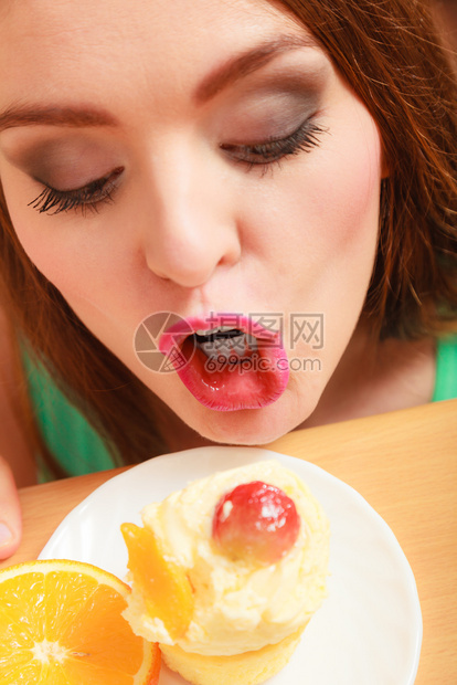 女人吃甜美的蛋糕上面有甜的奶油和水果图片
