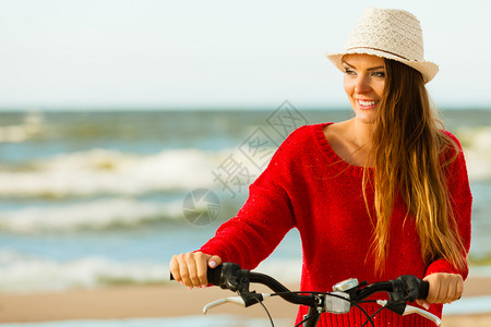 在海边骑自行车的年轻活跃女孩夏天在海上附近躺着笑的可爱女人时装旅游者在新鲜空气中时装女孩在户外骑自行车图片