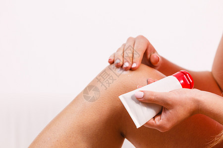 健身女子在伤痛的膝盖上涂膏油或用湿润的奶油处理皮肤运动训练健康和皮肤护理背景图片