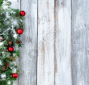 圣诞节背景雪覆盖长绿树枝礼物和白锈木上的红装饰品图片
